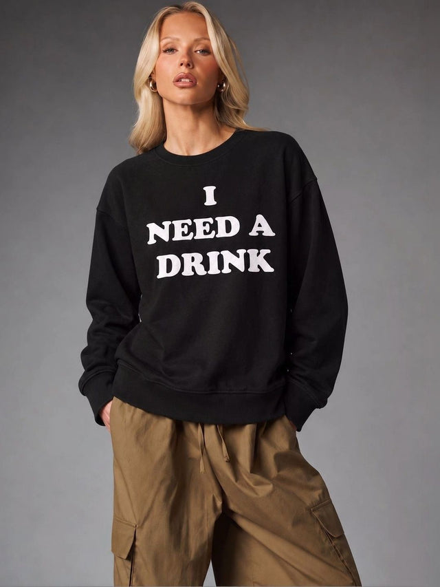 Front view of I Need A Drink Black Oversized Sweatshirt with white slogan print